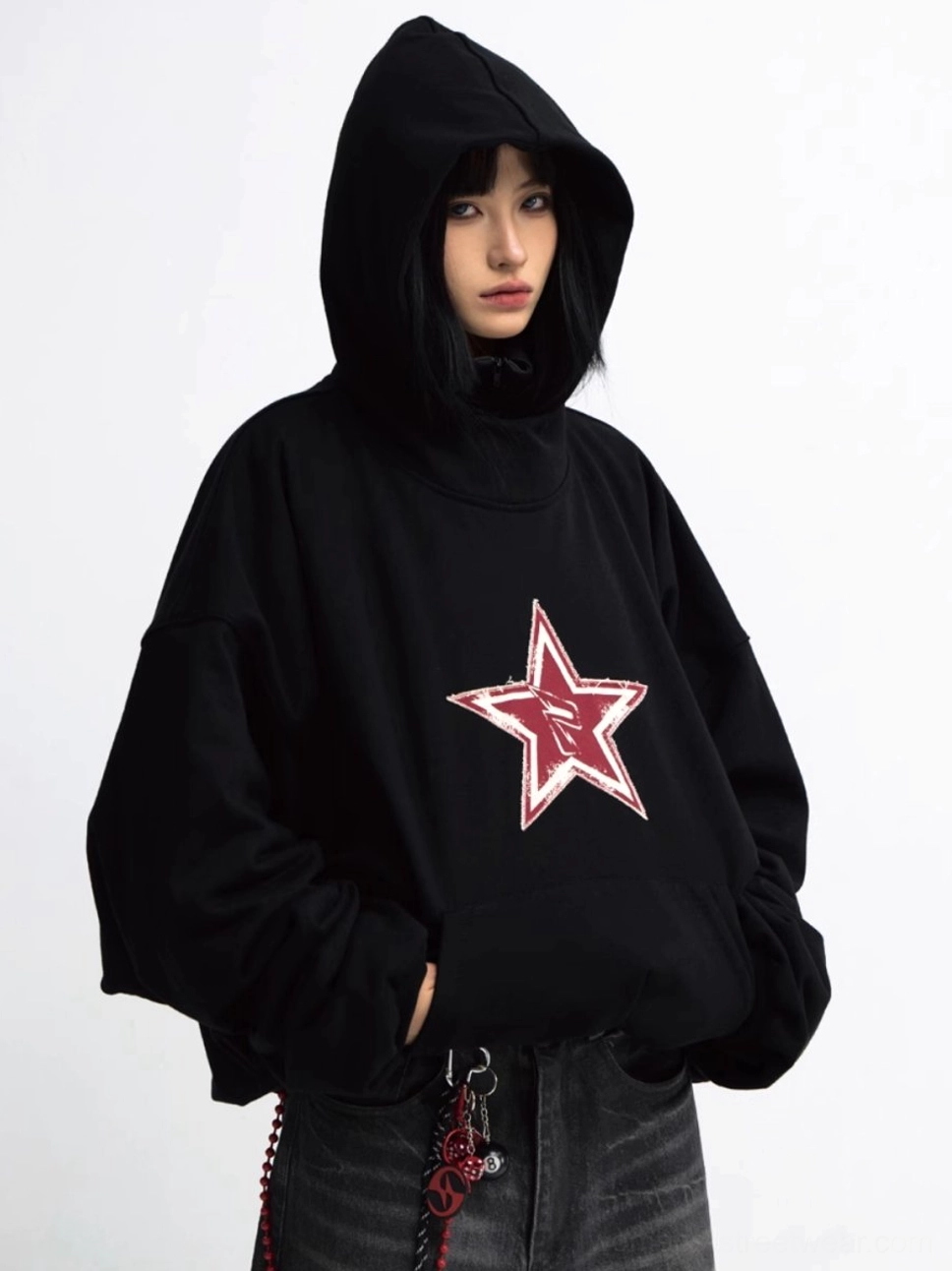 Close front view of an oversized black hoodie with red distressed five-pointed star chest graphic