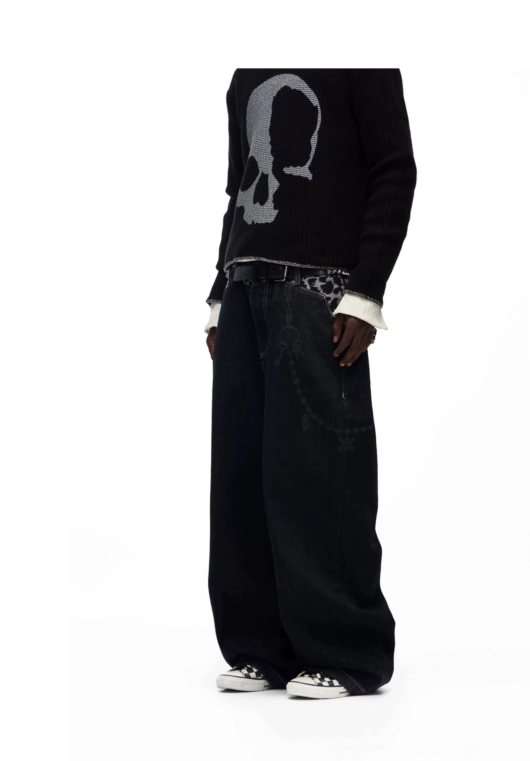Front side view of oversized black leopard waistband baggy jeans styled with a skull graphic knit sweater in an avant garde streetwear look