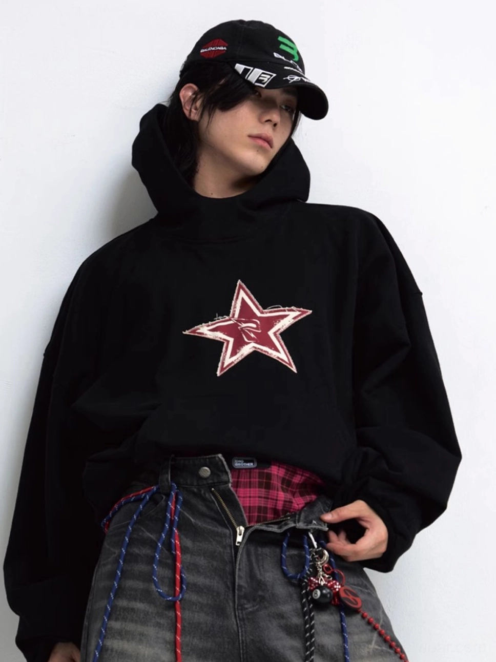 Front three-quarter view of an oversized black red star graphic hoodie with distressed chest print and layered streetwear styling