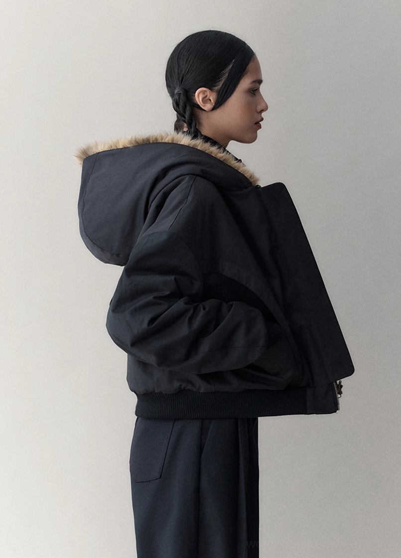 Side and back view of an oversized black reversible hooded winter jacket with dropped sleeves and cropped streetwear silhouette