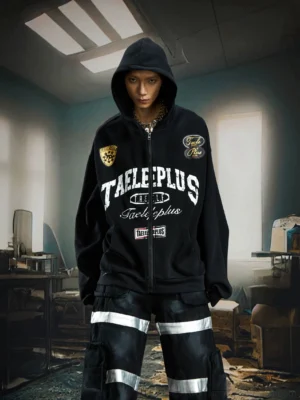 Black oversized varsity patch zip-up hoodie with hood up styled with reflective cargo pants front view