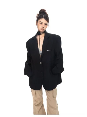 Front full-body view of an oversized black zip-pocket tailored blazer styled with a camisole and cargo pants for contemporary women's streetwear