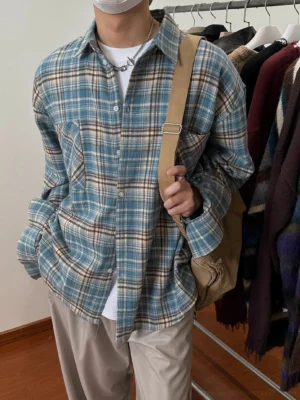 Model wearing an oversized blue brown plaid flannel shirt with drop shoulders over a white tee and beige loose pants in a casual streetwear outfit