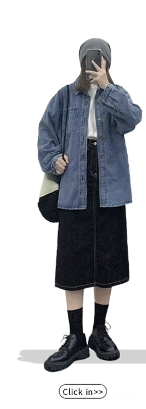 Back three-quarter view of an oversized blue denim shirt jacket styled with a black midi skirt, beanie, sneakers, and crossbody bag