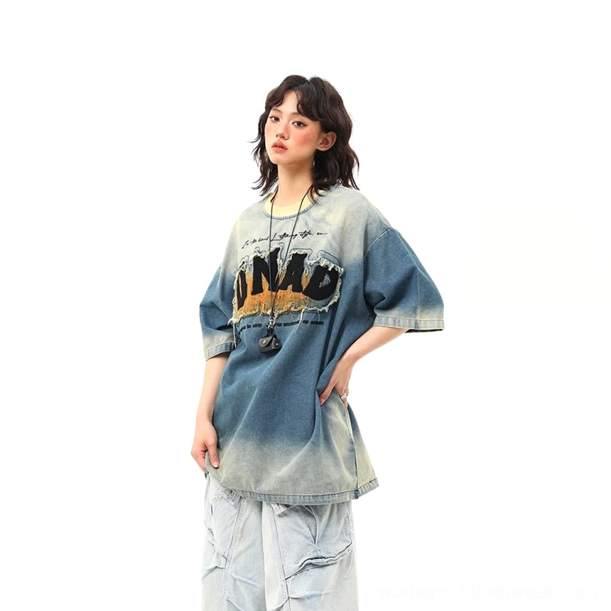 Side back view of an oversized blue distressed denim wash graphic T-shirt showing the relaxed silhouette, dropped shoulder, faded finish, and cargo styling