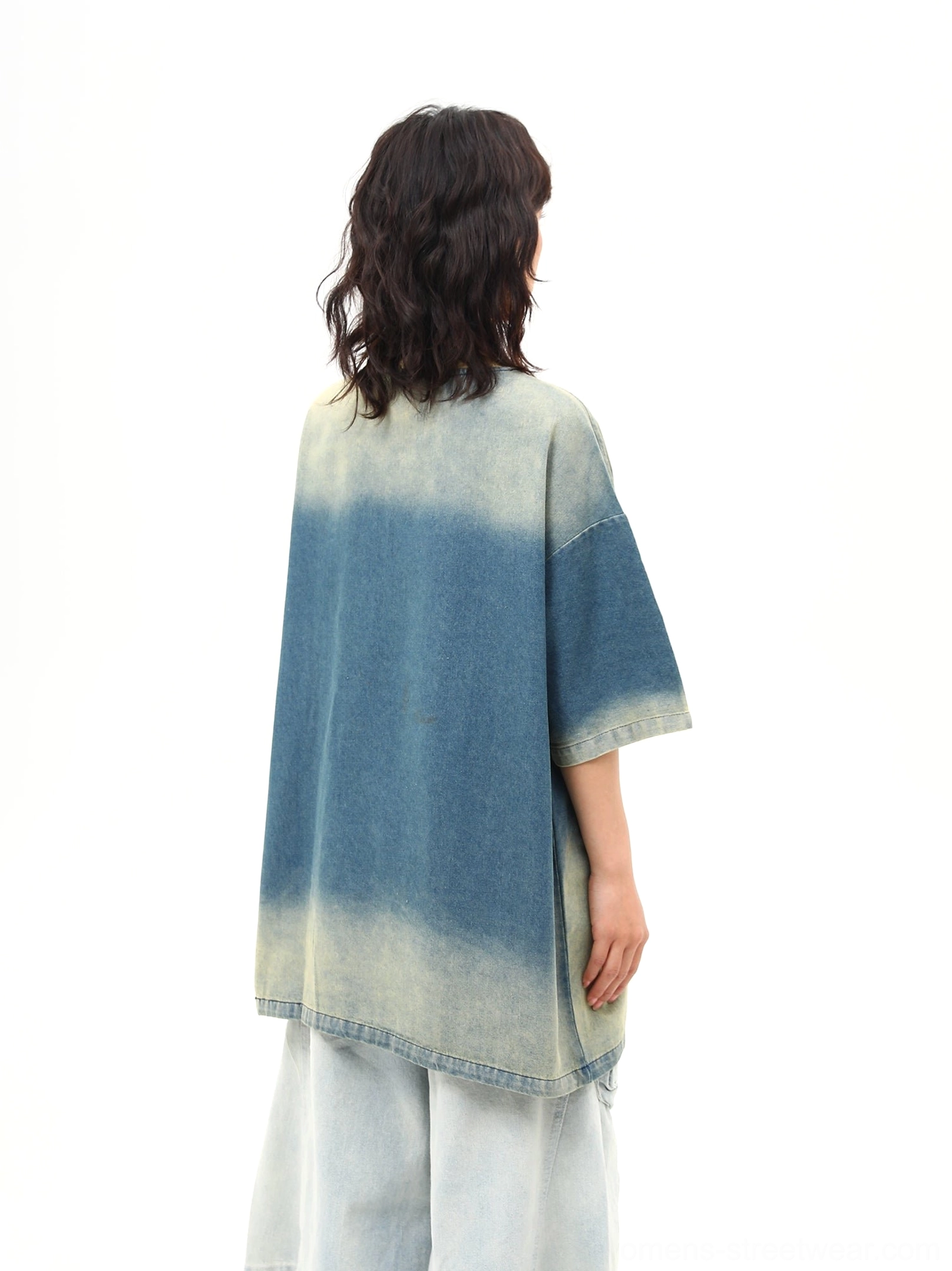 Back view of an oversized blue distressed denim wash T-shirt showing the faded gradient finish, loose drop-shoulder silhouette, and relaxed streetwear fit