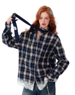 Three-quarter front view of an oversized blue plaid lace trim button-up shirt styled with wide-leg denim and a matching necktie