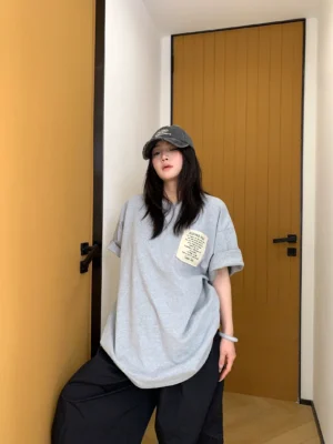 Three-quarter front view of heather gray oversized patch logo T-shirt with rolled sleeves and relaxed cocoon silhouette