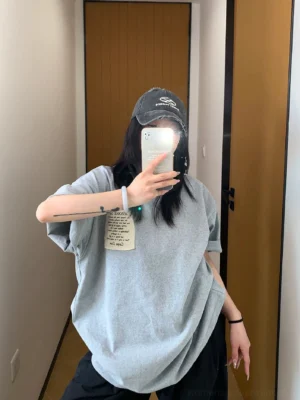 Heather gray oversized bubble fit patch logo T-shirt styled with black wide-leg pants and vintage baseball cap front view