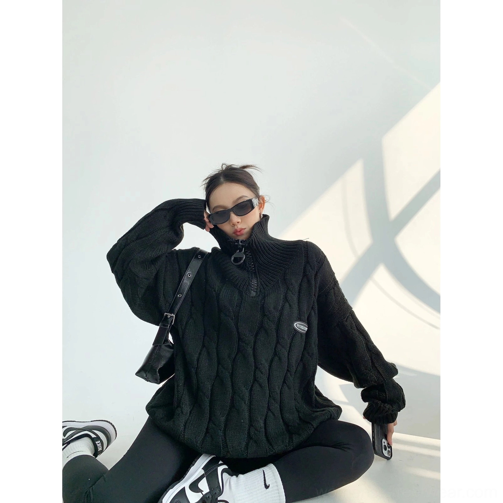 Black oversized cable knit quarter-zip stand collar sweater in a casual seated Korean streetwear look