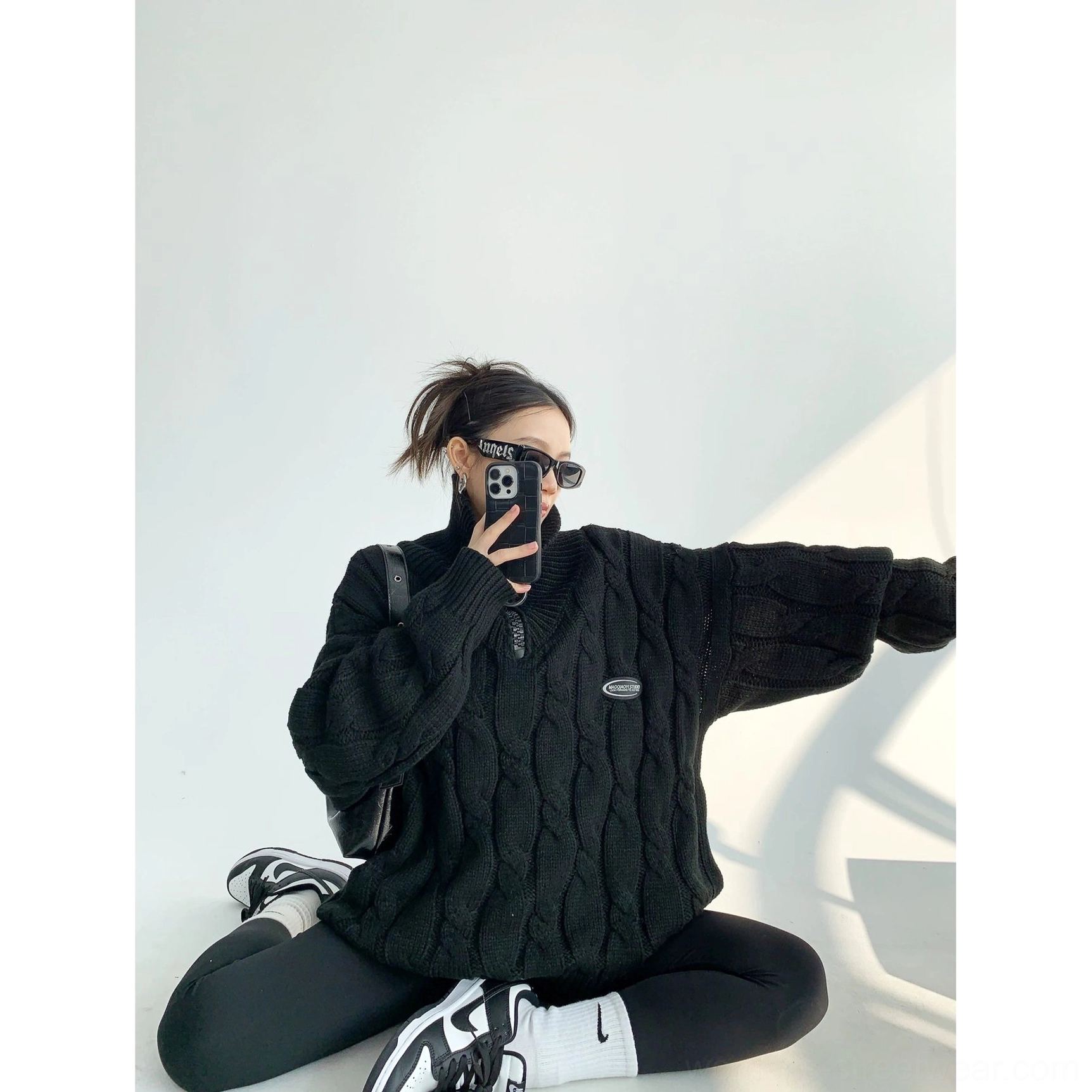 Black oversized cable knit quarter-zip sweater side view with slouchy sleeves and curved hemline