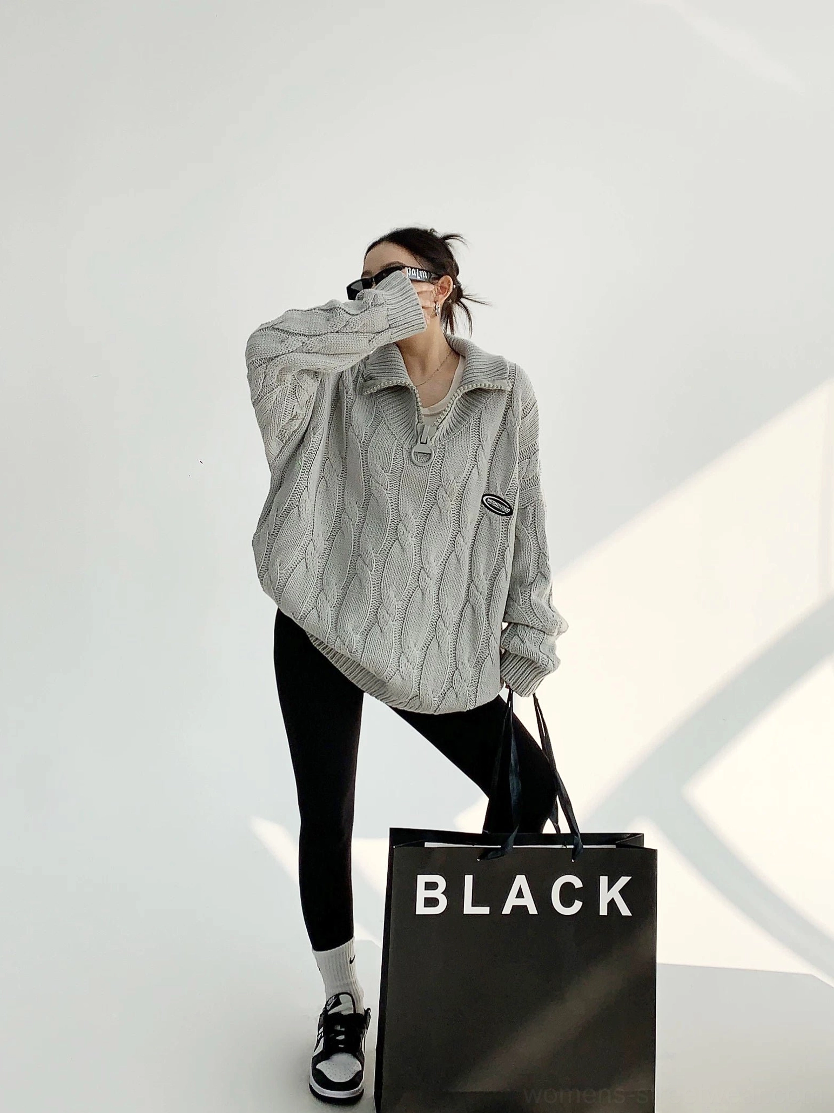 Gray oversized cable knit quarter-zip sweater styled with black leggings and sneakers in a full front streetwear outfit