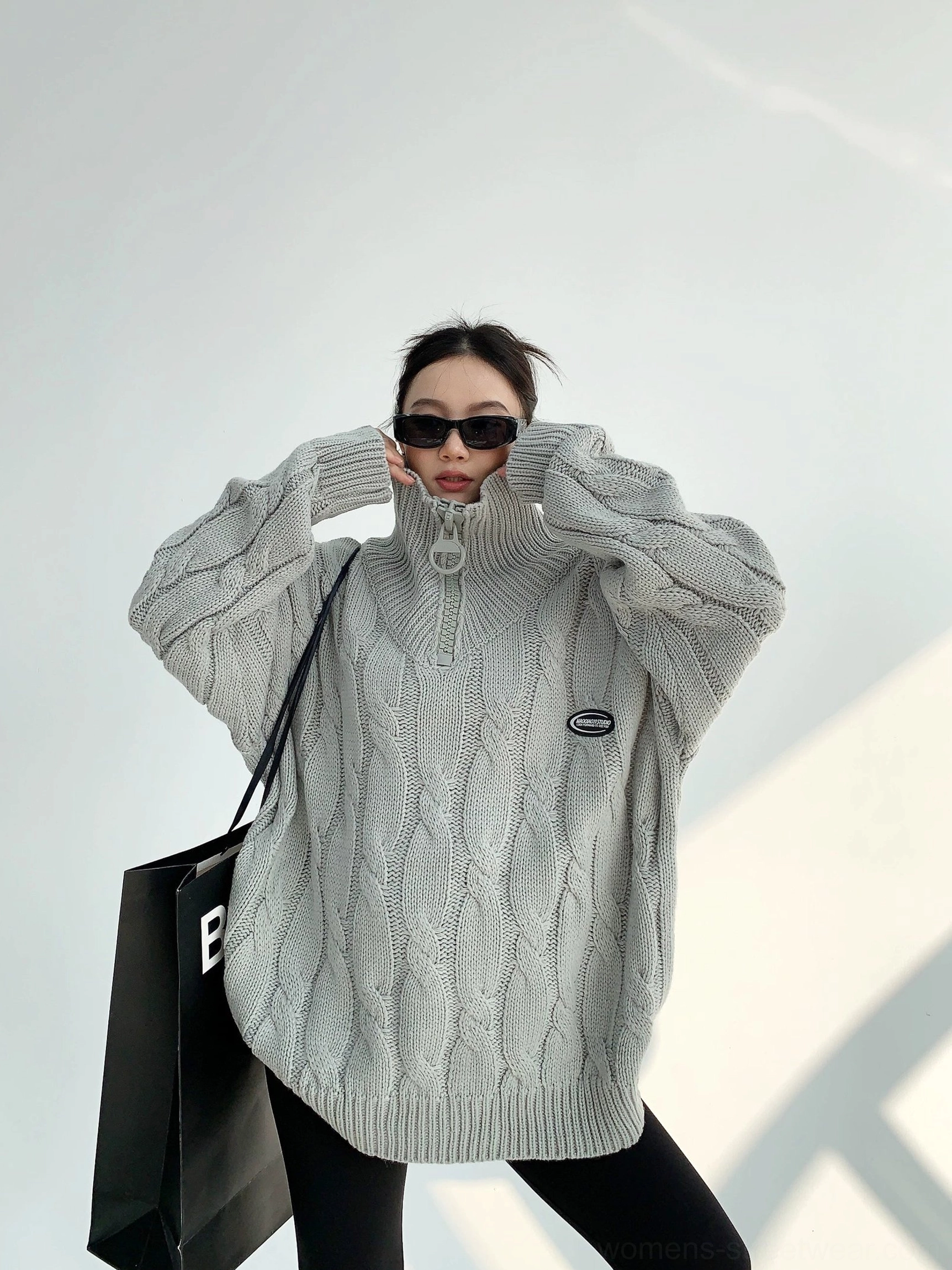 Gray oversized quarter-zip cable knit sweater with relaxed long sleeves and curved hem