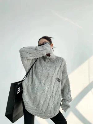 Gray oversized cable knit quarter-zip sweater with high stand collar shown in three-quarter side view