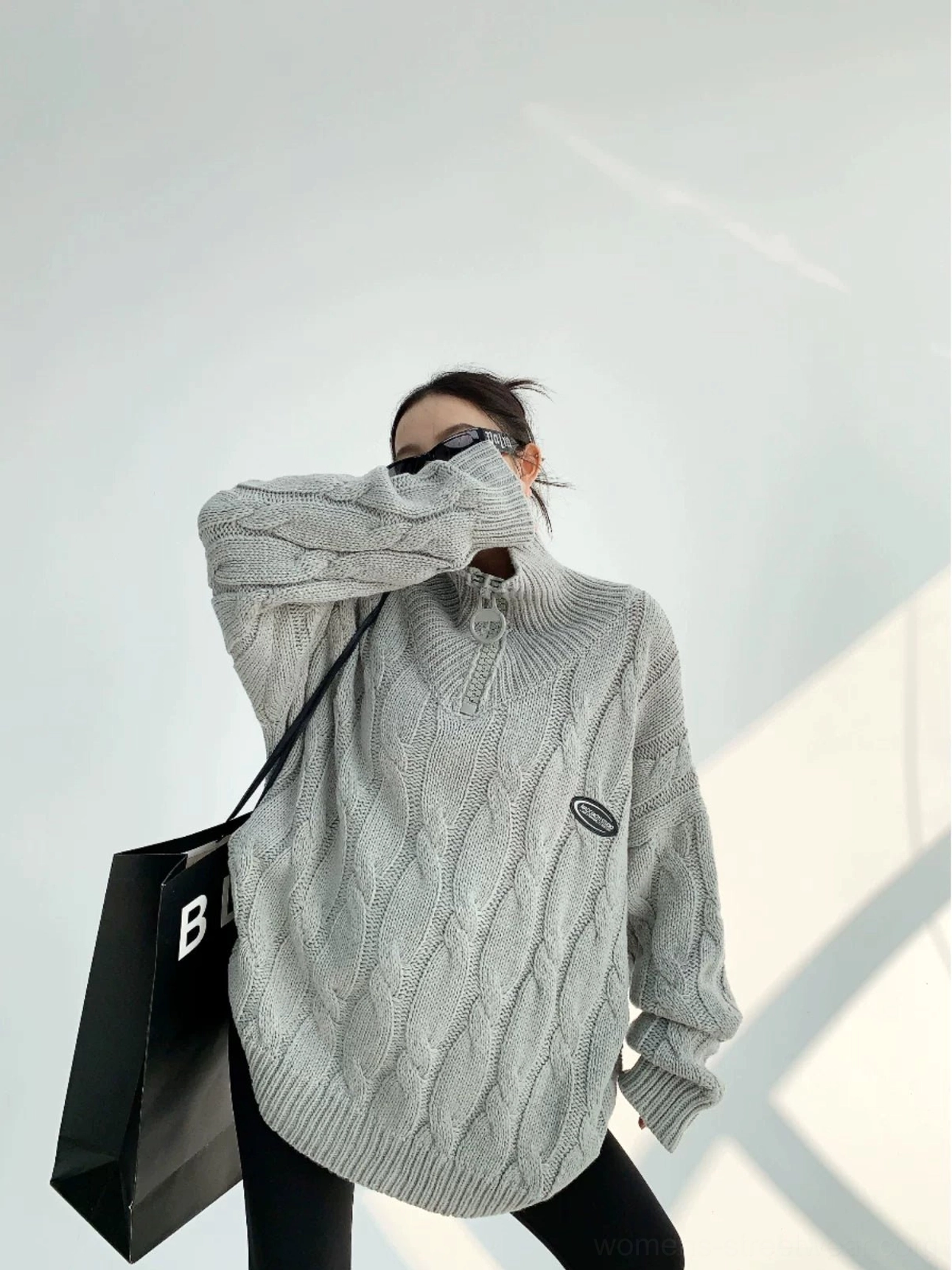 Gray oversized cable knit quarter-zip sweater with high stand collar shown in three-quarter side view
