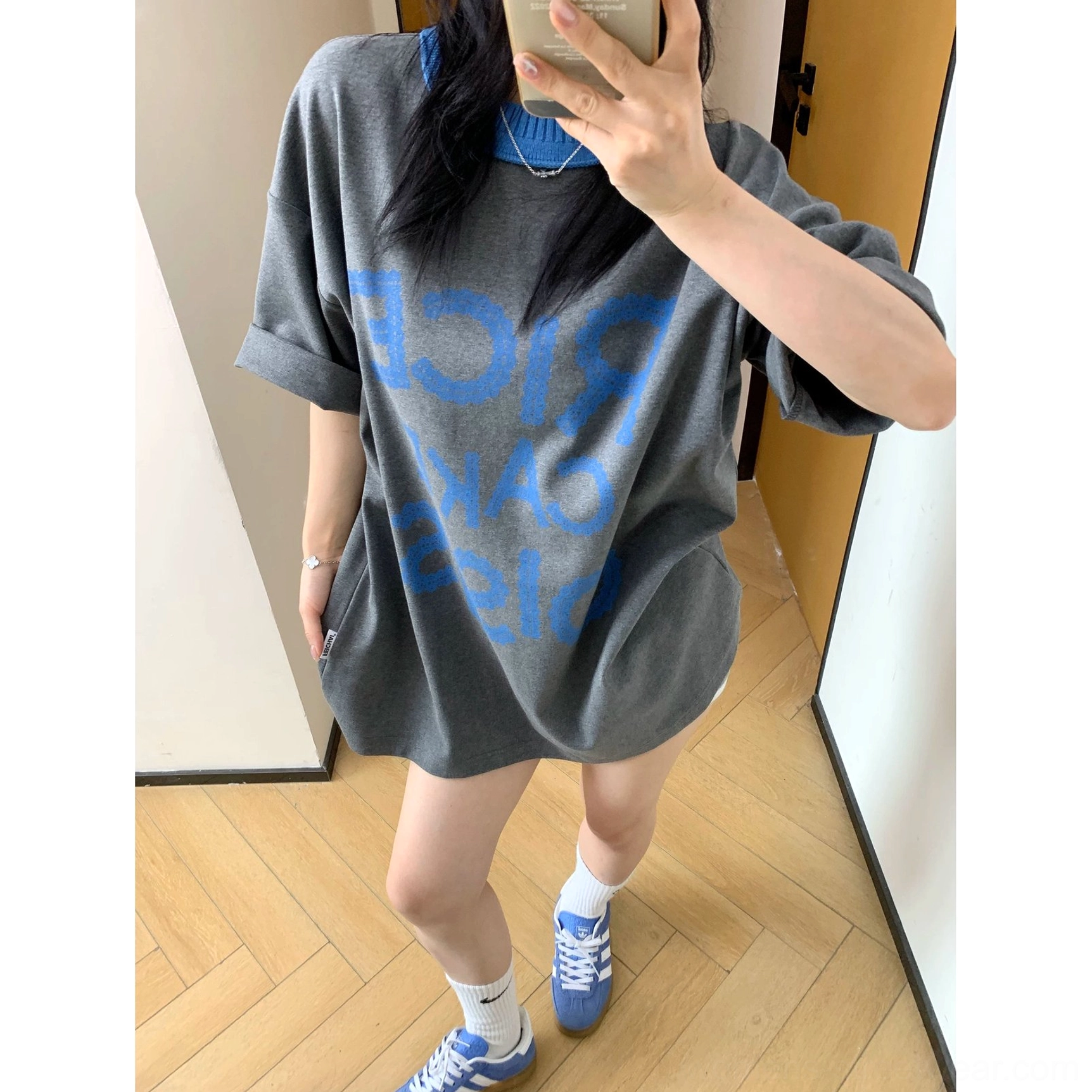 Oversized charcoal graphic T-shirt with reversed blue front print styled with white socks and blue retro sneakers in a casual streetwear outfit