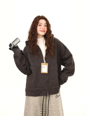 Woman wearing an oversized dark charcoal marled fleece zip-up hoodie with cream mock-neck top and striped wide-leg pants in a casual Seoul-inspired streetwear outfit
