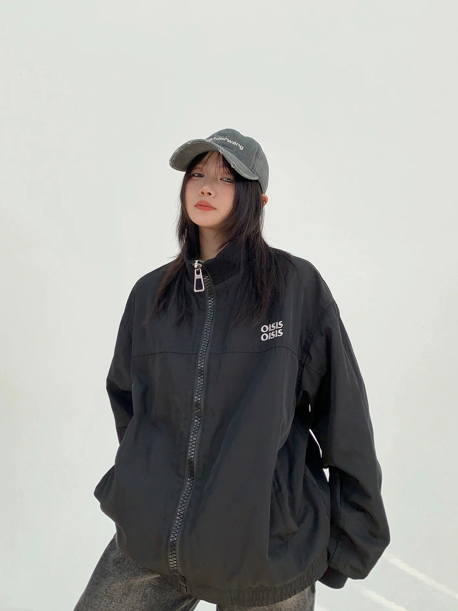 Black oversized cloud shell windbreaker jacket for women in front three-quarter view featuring stand collar, full zipper and chest logo detail