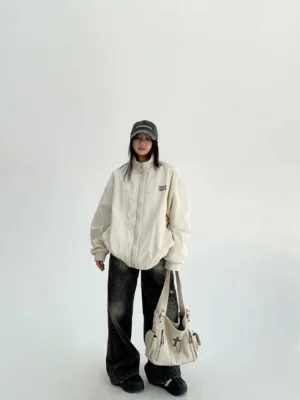 Off-white women's oversized cloud shell windbreaker jacket full front outfit view with zip front, stand collar, jeans and shoulder bag