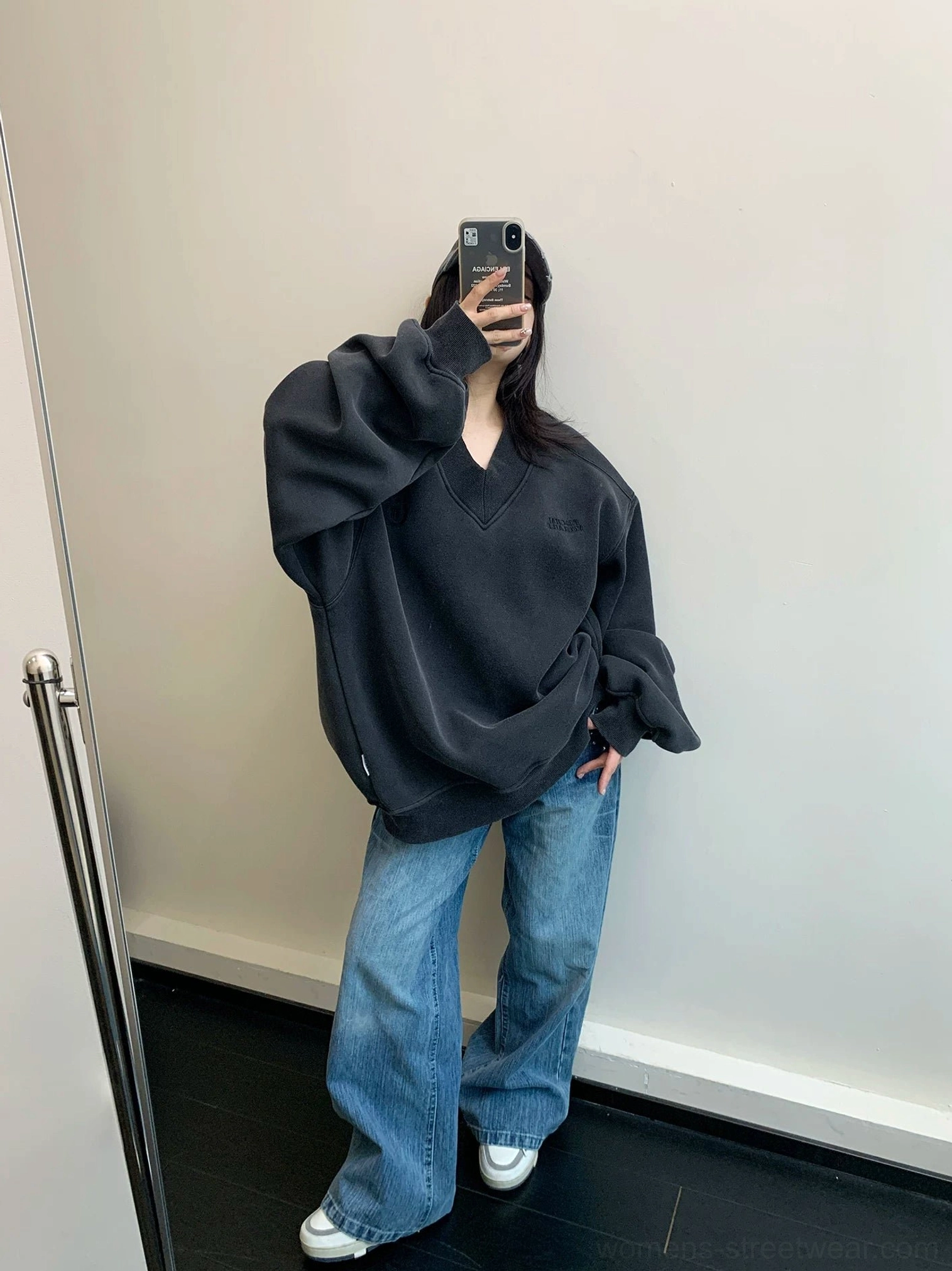 Black oversized collegiate crest V-neck fleece sweatshirt styled with relaxed blue wide-leg jeans