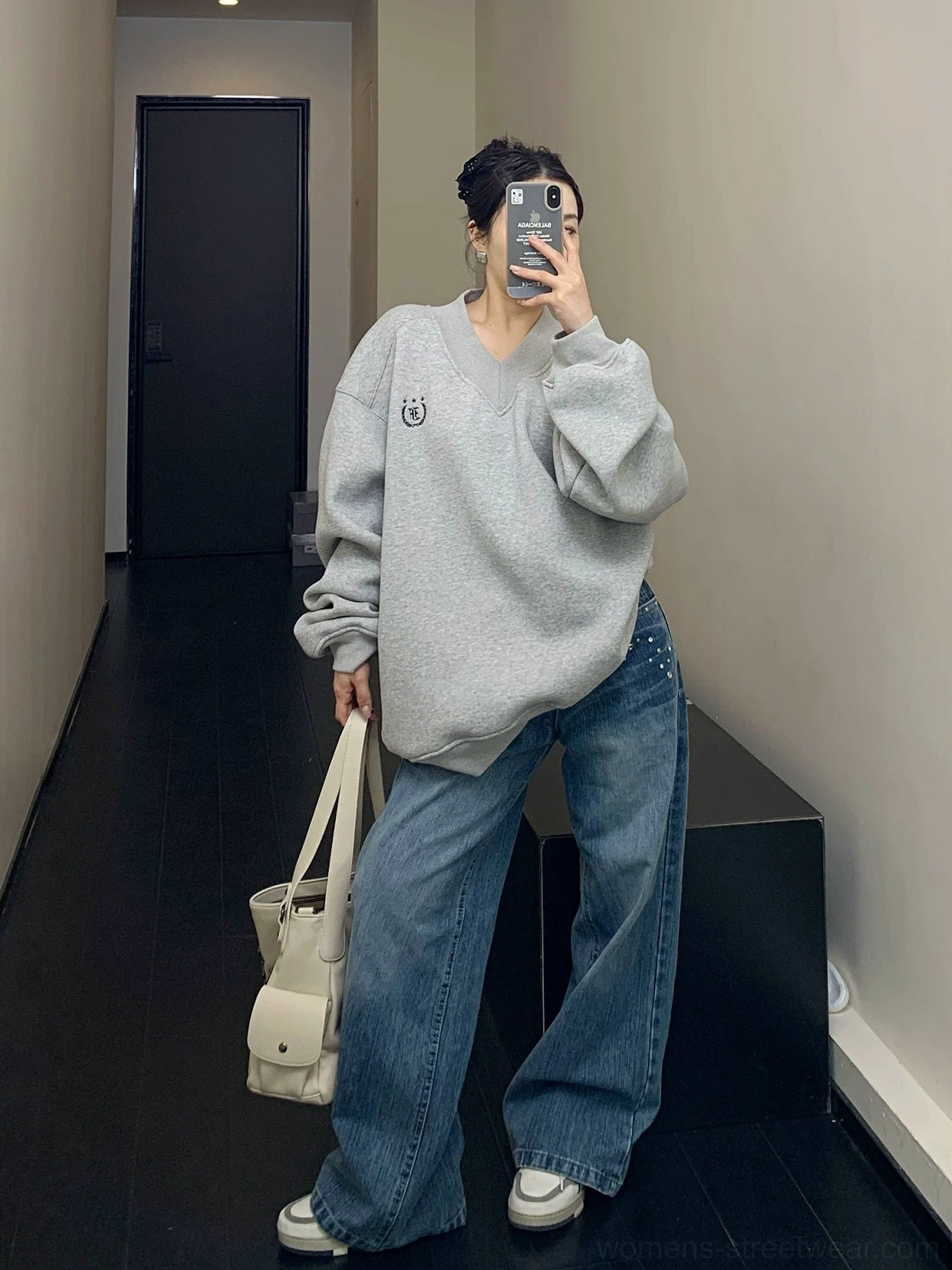 Full body view of heather gray oversized V-neck fleece sweatshirt with wide-leg blue jeans and white sneakers