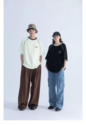 Front full-body view of oversized contrast raglan sleeve streetwear T-shirt worn by two casual unisex models with embroidered chest detail and relaxed loose fit