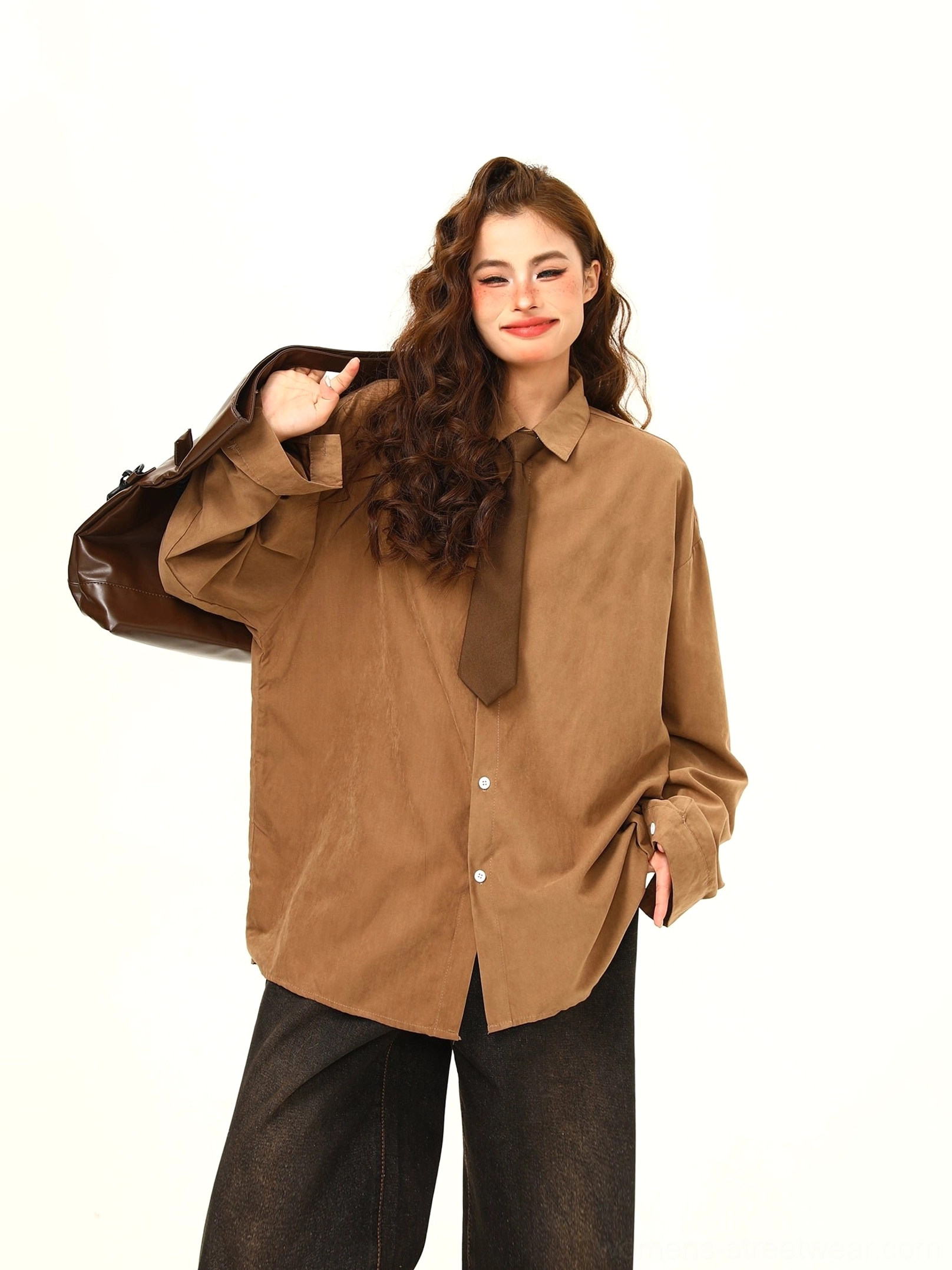 Front three-quarter view of a woman wearing a tan brown oversized corduroy shirt with matching brown tie, black wide-leg jeans, and Korean streetwear styling