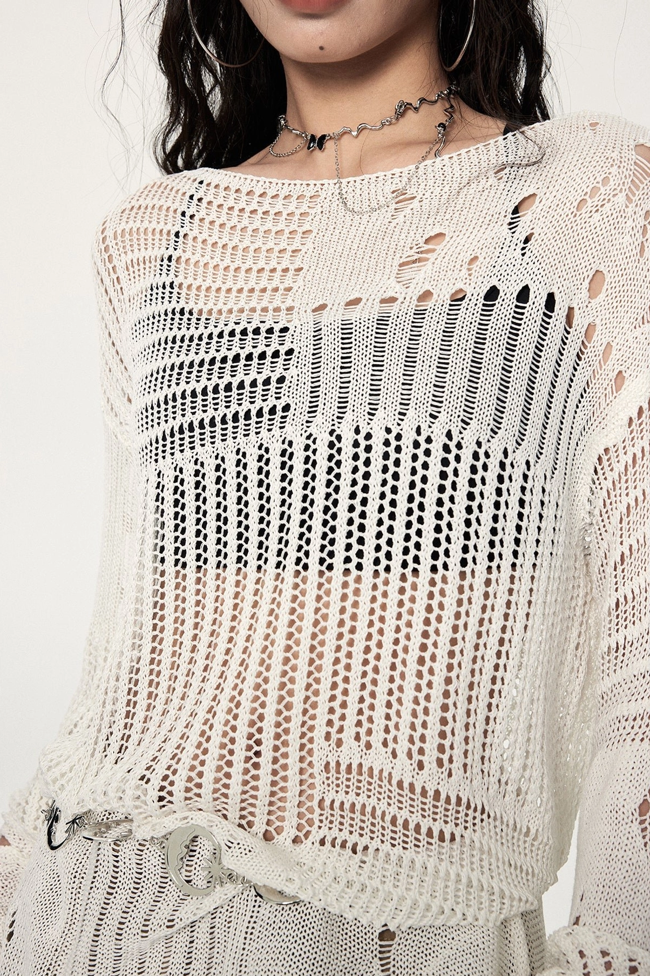 Oversized crochet sweater with distressed cut-outs, asymmetric hemline, exposed layering effect, and modern Seoul-inspired streetwear aesthetic