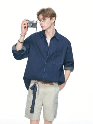 Male model wearing an oversized dark denim streetwear shirt with rolled cuffs styled with khaki cargo shorts and a bandana belt
