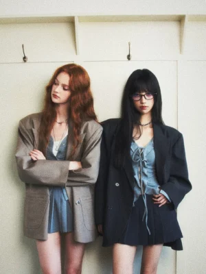 Oversized double-breasted checked streetwear blazer in charcoal gray and earth taupe styled by two women with lace-up denim dresses
