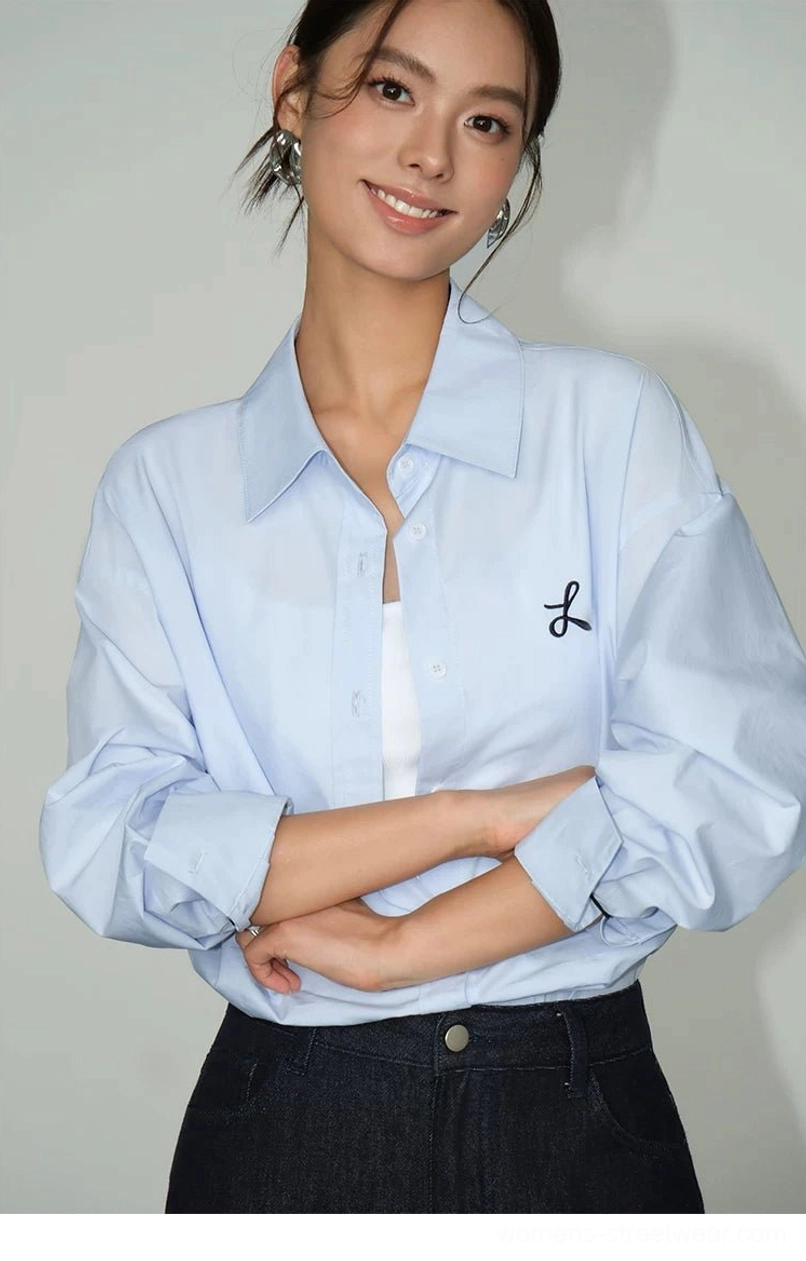 Light blue oversized button-down shirt with small black bow embroidery and white inner top