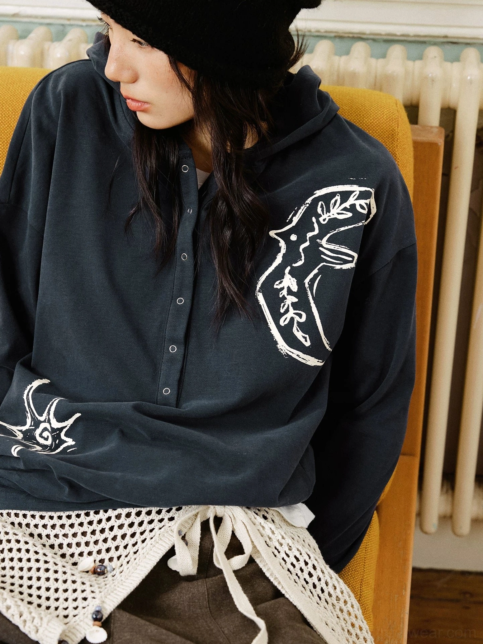Black oversized embroidered graphic Henley polo shirt with hand-drawn animal and star embroidery styled with a newsboy cap