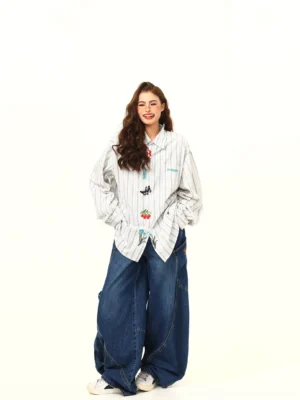 Full-body front view of an oversized white and gray embroidered striped shirt with butterfly cherry and floral details styled with wide-leg denim pants