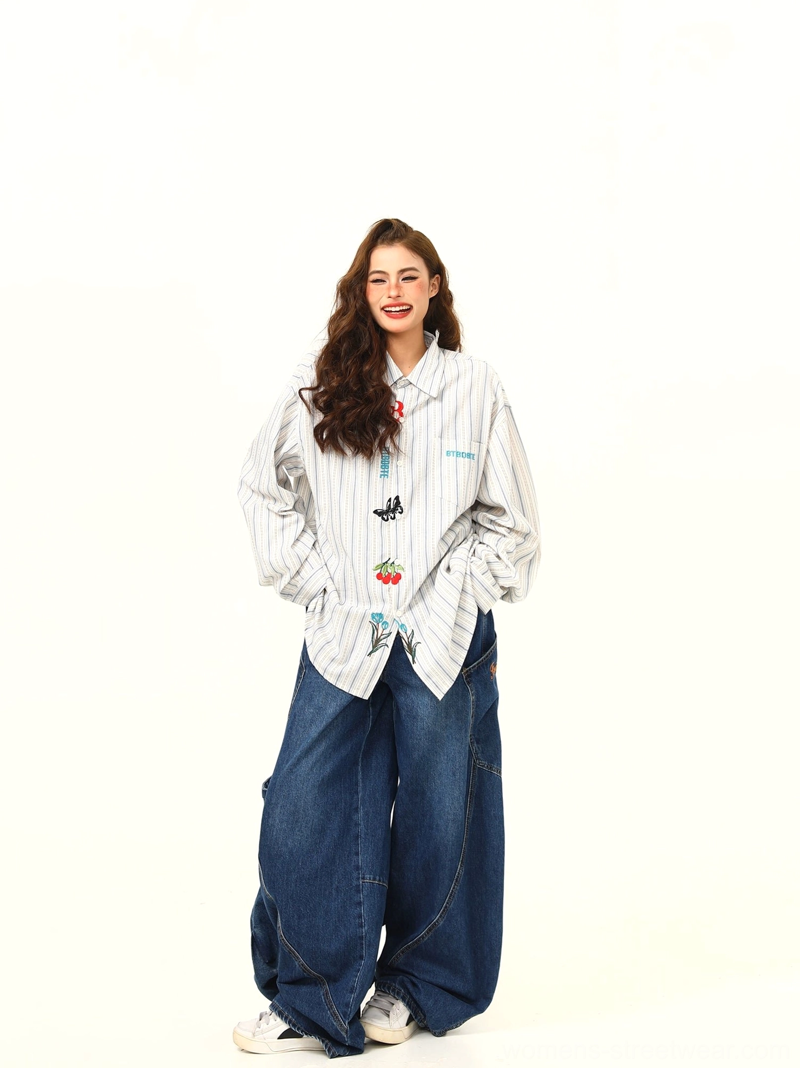 Full-body front view of an oversized white and gray embroidered striped shirt with butterfly cherry and floral details styled with wide-leg denim pants