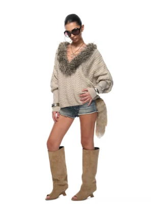 Front view of a relaxed oversized faux fur collar cable knit sweater styled with denim shorts and knee-high suede boots