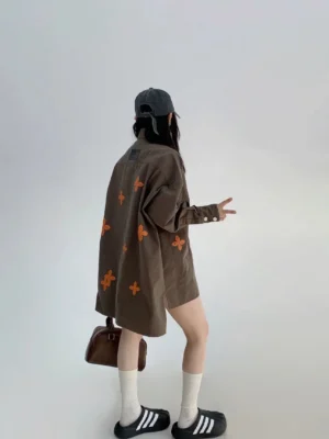 Back view of an oversized coffee green floral embroidered button shirt with orange flower motifs, long sleeves, and relaxed Acubi streetwear silhouette