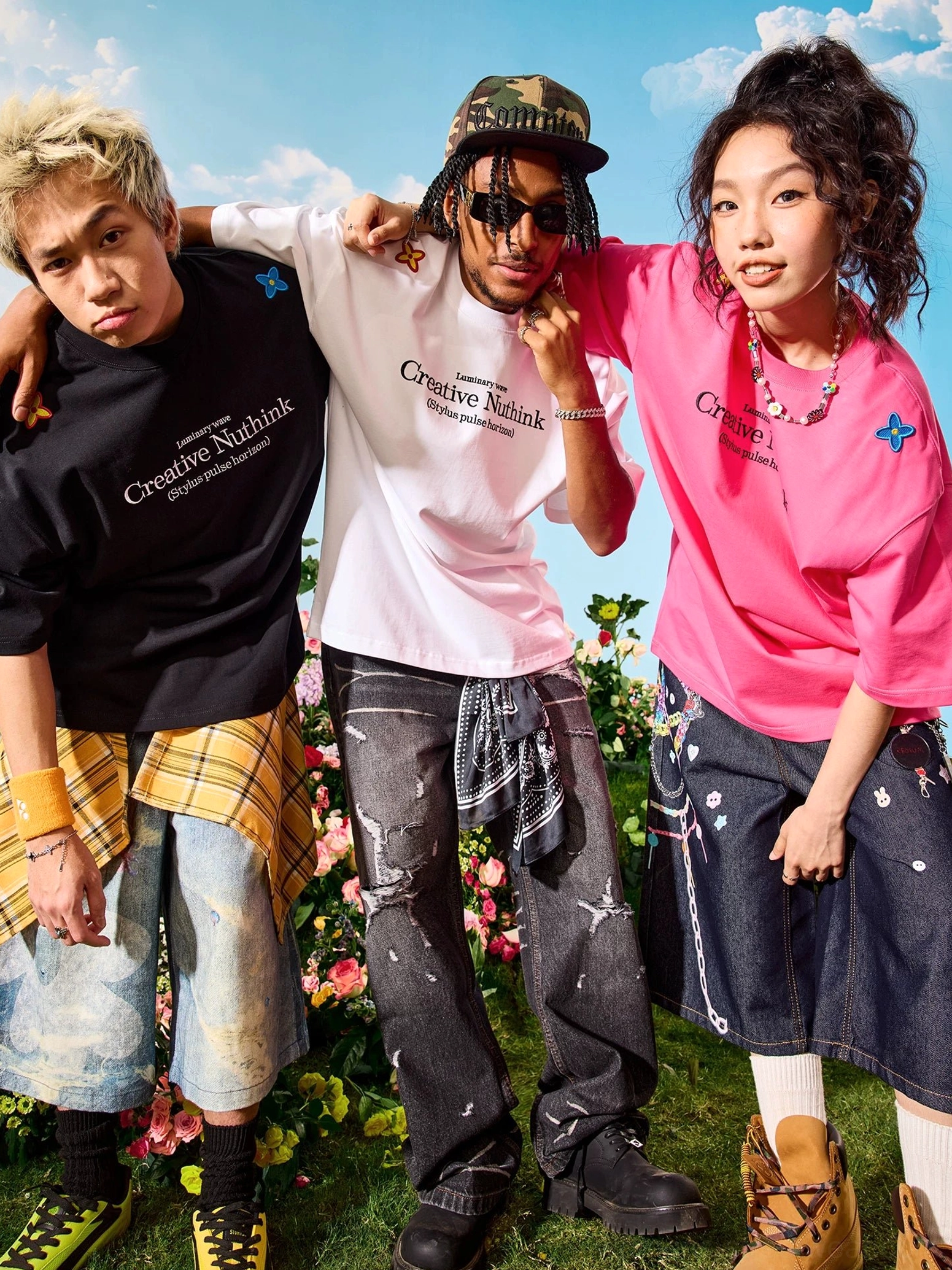 Group of models wearing oversized floral graphic streetwear T-shirts in multiple colorways in an outdoor flower field