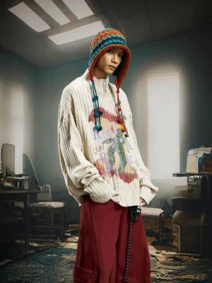 Oversized apricot garden graphic ribbed zip knit cardigan worn in a three-quarter front view with red wide-leg streetwear pants