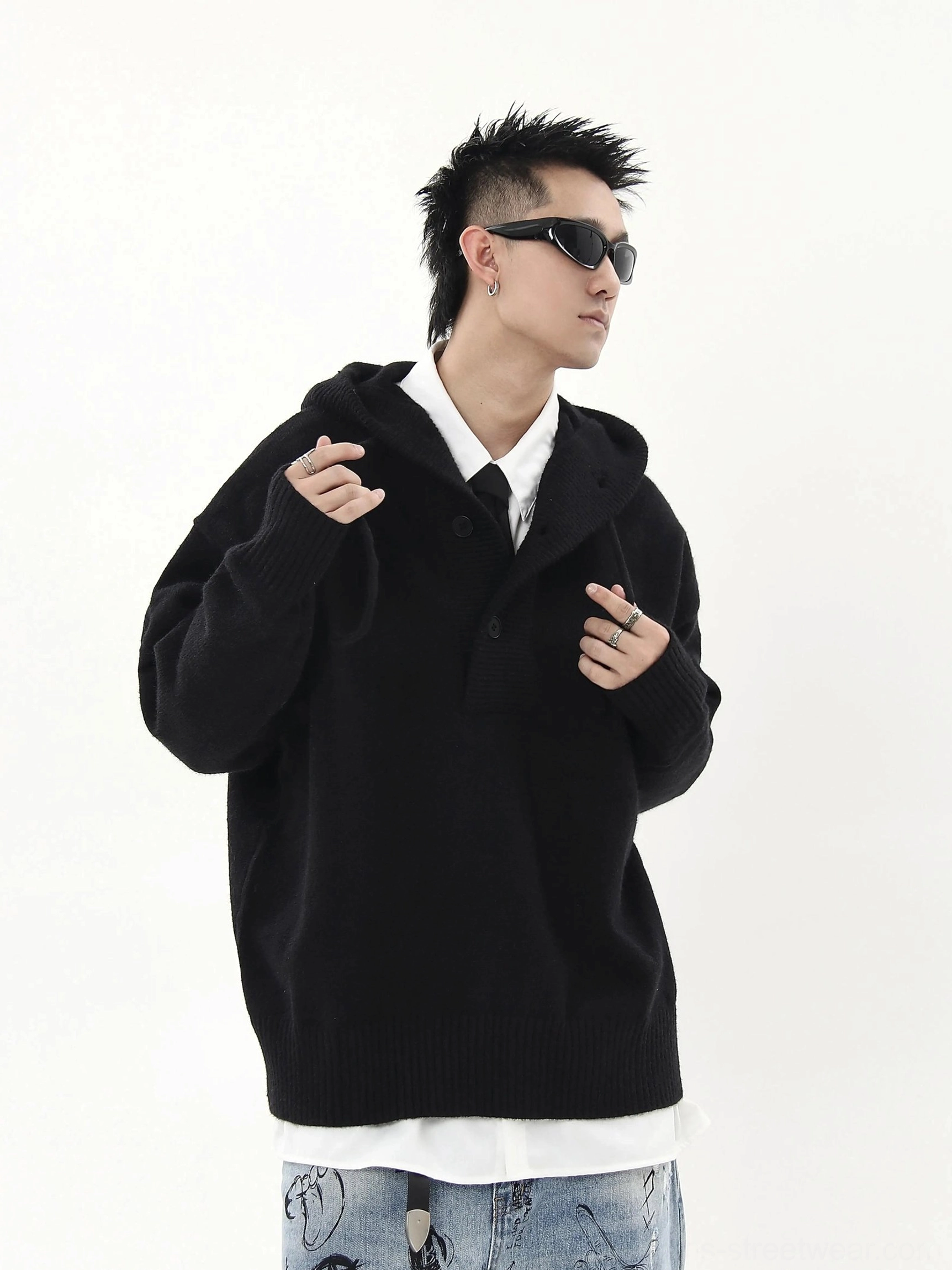 Black oversized knit half-button hoodie sweater close-up with structured hood, button placket, and white shirt layering