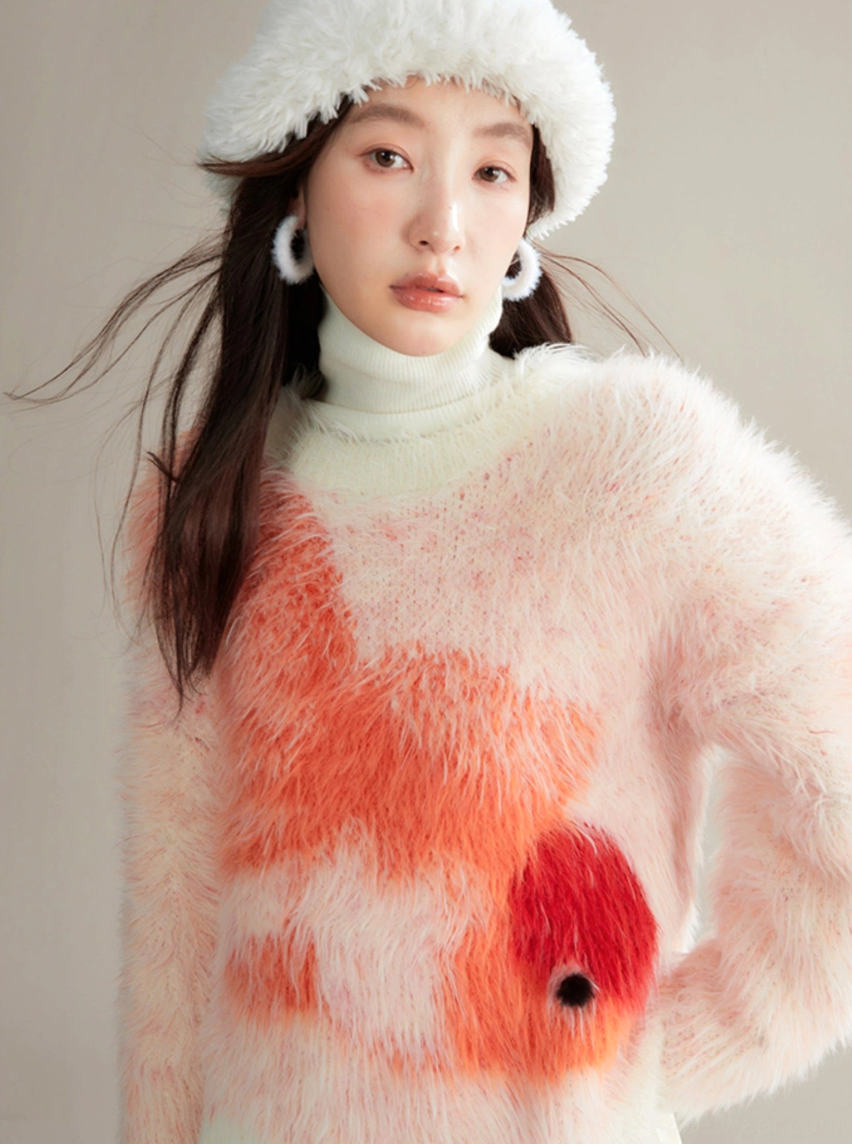 Three-quarter view of oversized koi fish fuzzy sweater styled with white bucket hat and hoop earrings