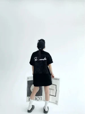 Black oversized script T-shirt rear full body view showing tonal floral lace back panel and bold white script