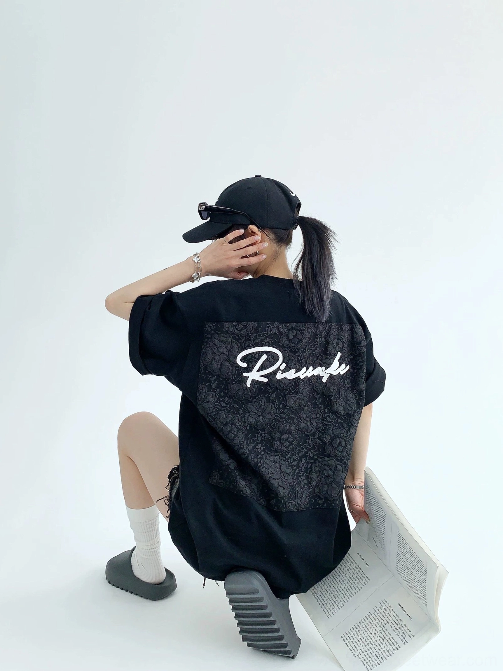 Black heavyweight oversized streetwear T-shirt side back view showing floral lace appliqué script design