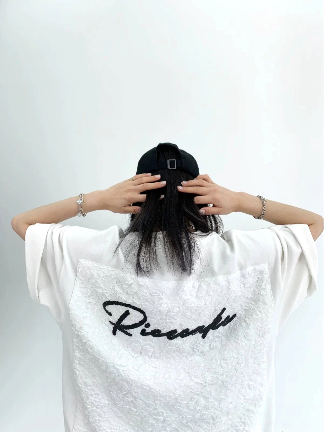 White oversized lace panel script streetwear tee back view with embossed floral appliqué and black cursive lettering