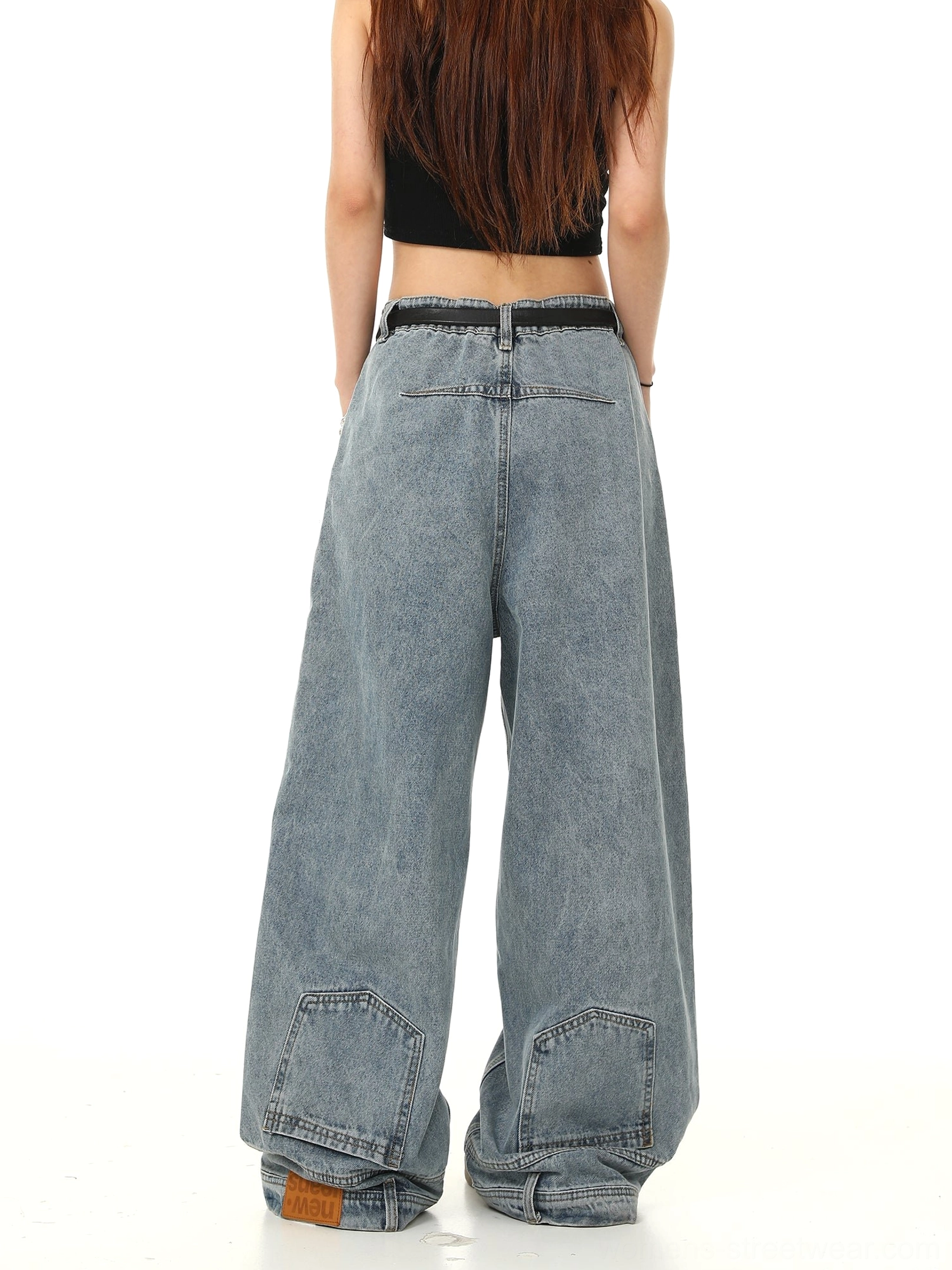 Back three-quarter view of oversized light blue baggy jeans with reinforced rear pockets, wide-leg streetwear shape, long hem, and belt styling