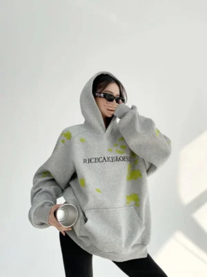 Gray oversized lime splatter graphic hoodie with RICECAKE and OISIS chest lettering, kangaroo pocket, and relaxed Korean streetwear fit
