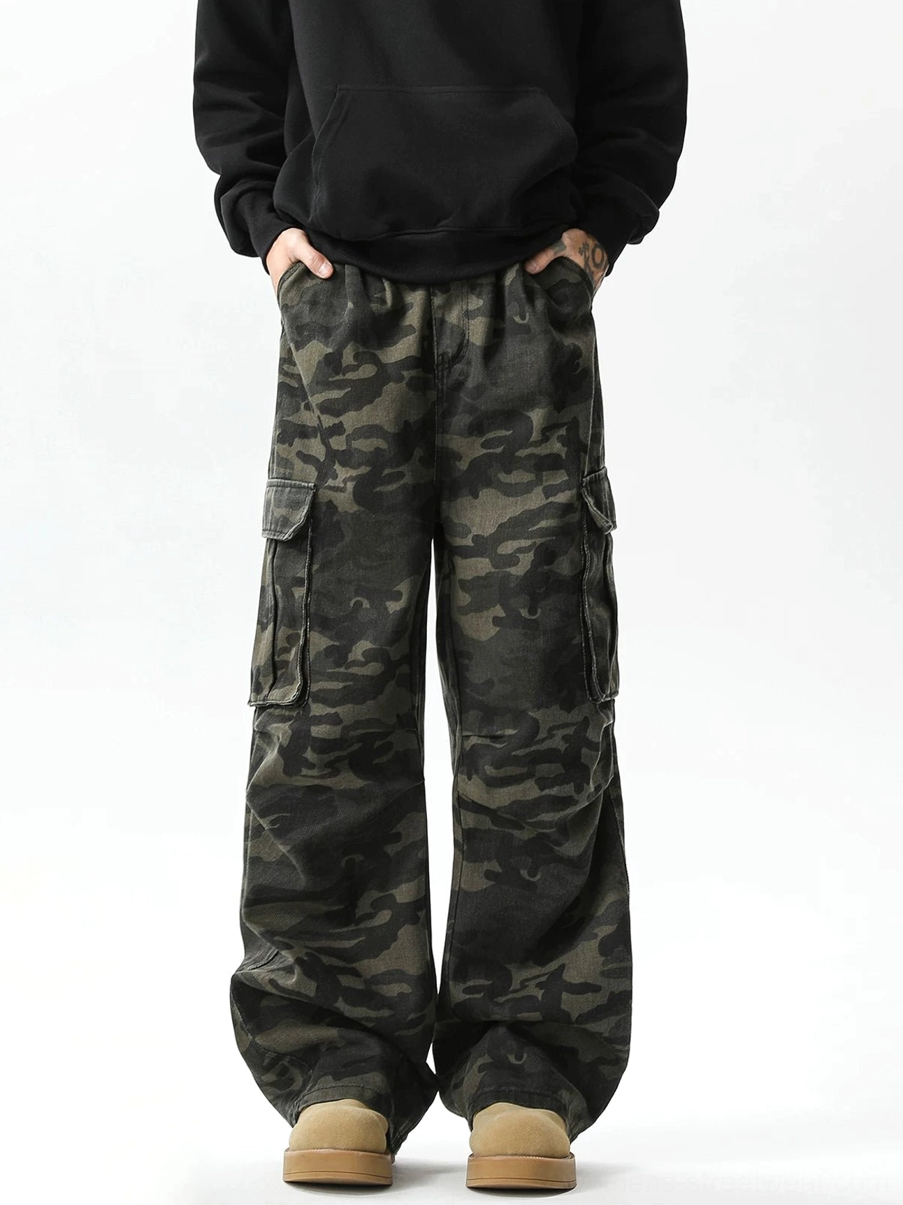 Full front view of oversized military camouflage wide-leg pants styled with a black hoodie and tan work boots for an urban utility outfit