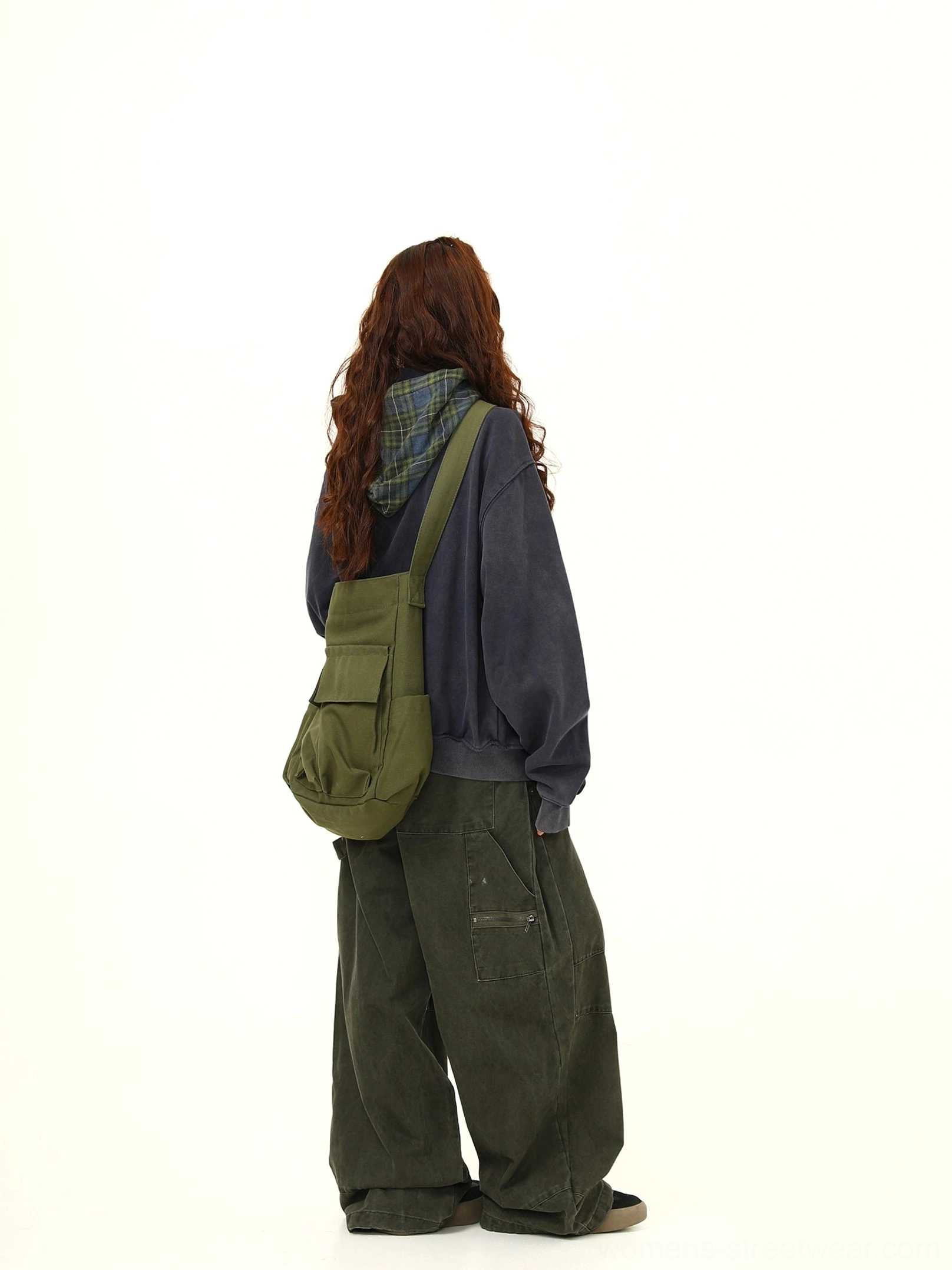 Back view showing the loose oversized silhouette of a navy hooded zip jacket styled with cargo pants