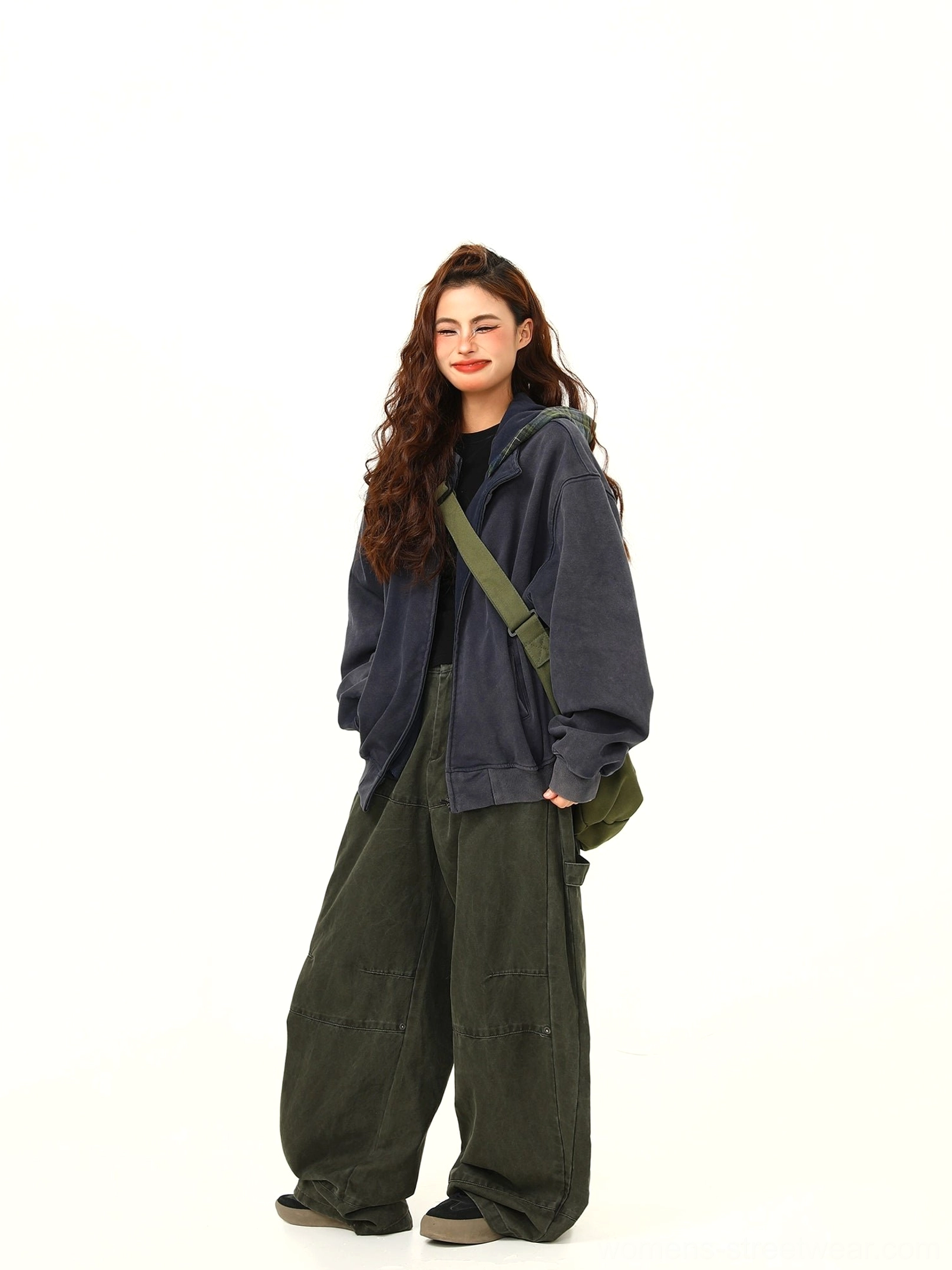 Three-quarter view of a relaxed oversized navy zip hoodie jacket styled with wide-leg cargo pants and a crossbody bag