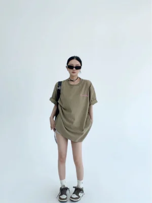 Oversized light brown streetwear graphic T-shirt shown from the front with sunglasses, relaxed drop shoulders, rolled sleeves, and subtle chest print