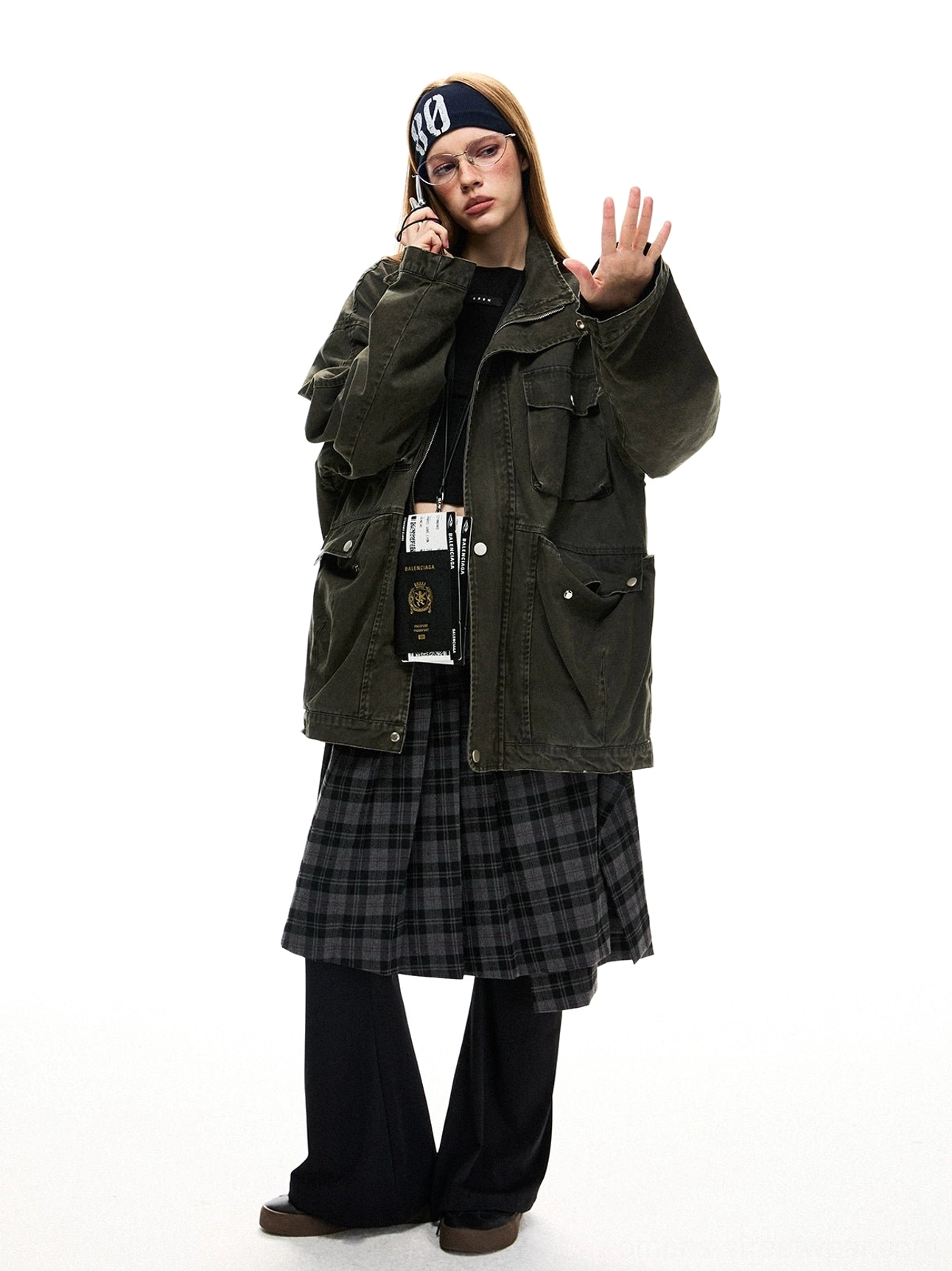 Full-body front view of a woman wearing an oversized olive green utility jacket with cargo flap pockets, relaxed shoulders, and layered streetwear styling